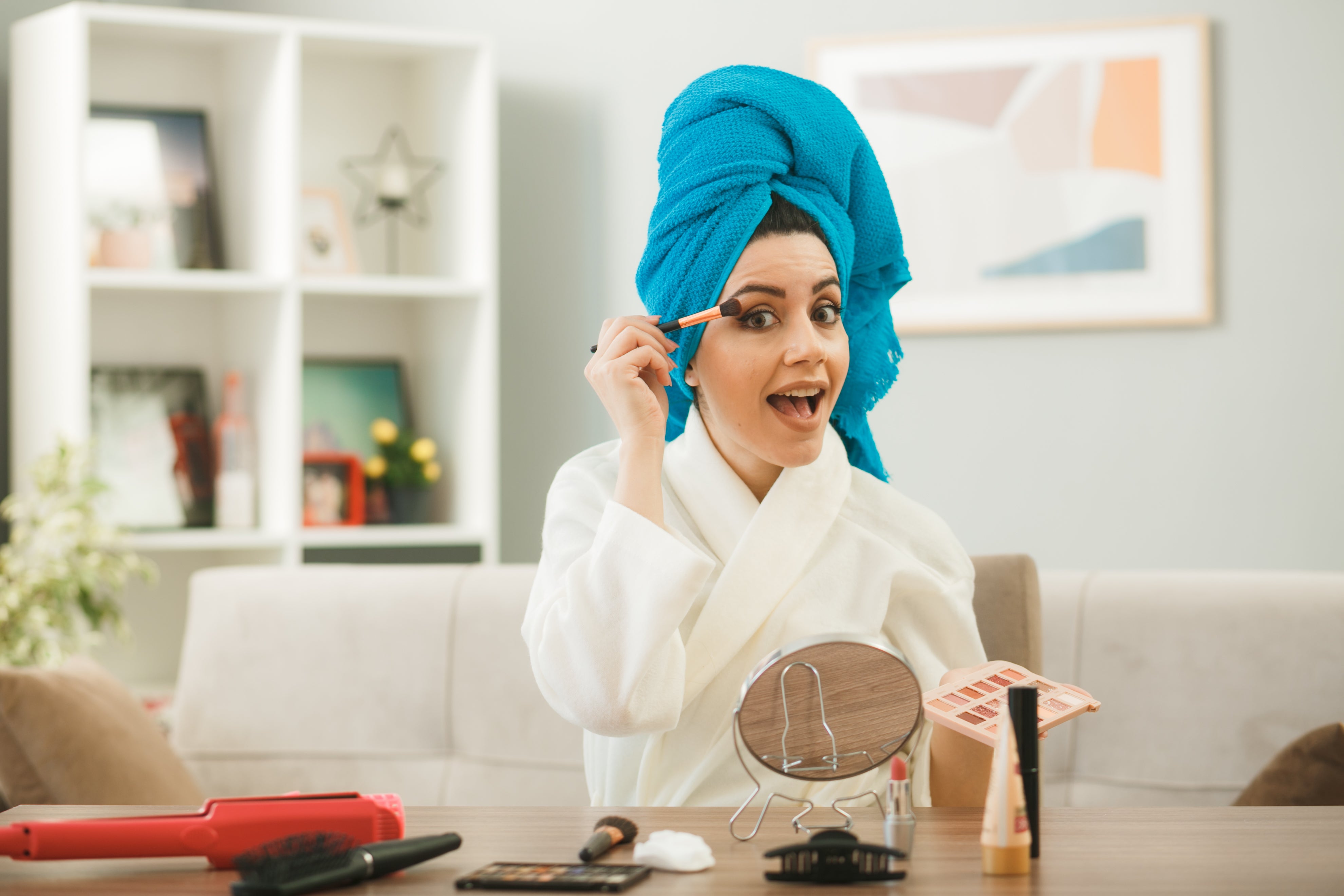 excited-young-girl-applying-eyeshadow-with-makeup-brush-sitting-table-with-makeup-tools-living-room.jpg